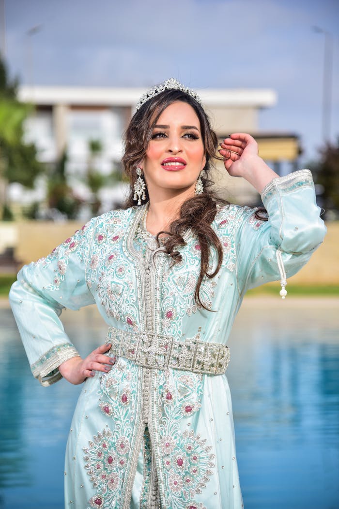 Beautiful woman in a traditional beaded caftan posing outdoors by a pool.